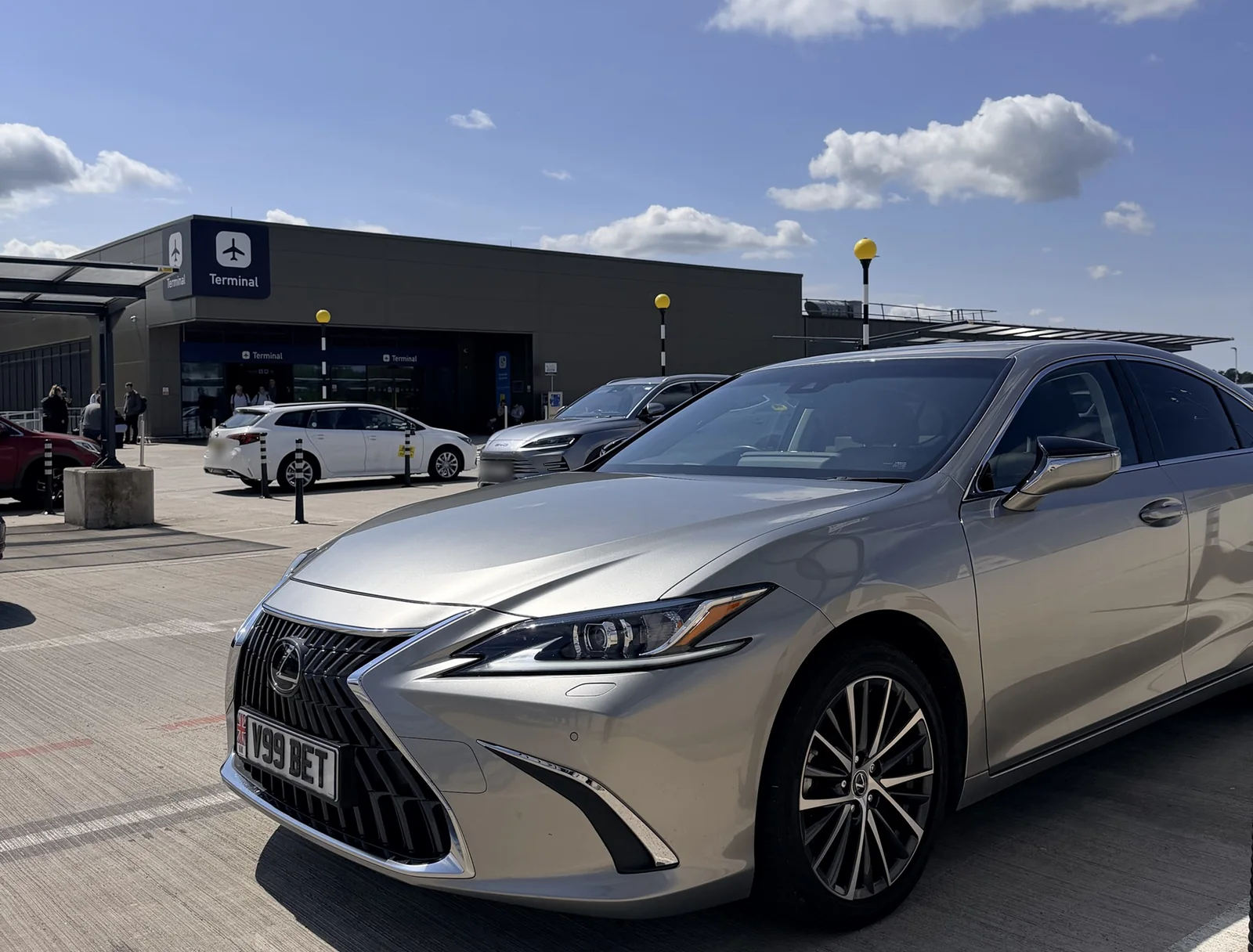 Beyond Elite Travel executive Lexus saloon in the sunshine outside the Bristol Airport terminal